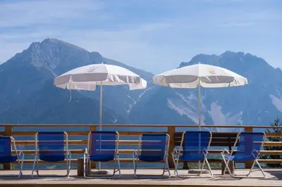 a group of chairs and umbrellas on a deck at Rifugio La Para in San Vigilio Di Marebbe