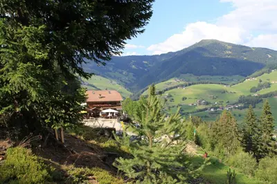 a view of a valley with a building and mountains at Rifugio La Para in San Vigilio Di Marebbe
