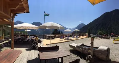a patio with tables and chairs and umbrellas at Rifugio La Para in San Vigilio Di Marebbe