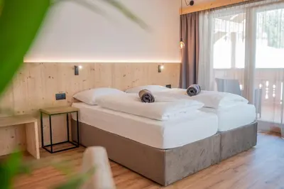 a bedroom with two beds with white sheets at Rifugio La Para in San Vigilio Di Marebbe
