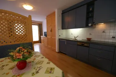 a kitchen with a table with a vase of flowers on it at Appartamenti Residence Pars in Badia