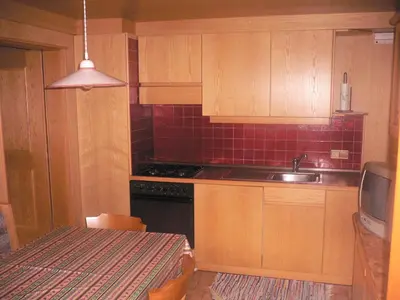 a kitchen with wooden cabinets and a sink and a table at Appartamenti Residence Pars in Badia