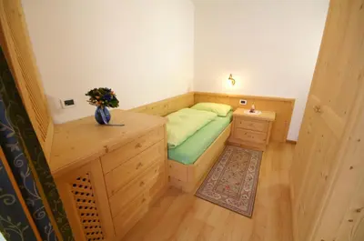 a small bedroom with a bed and a desk at Appartamenti Residence Pars in Badia