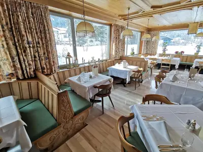a restaurant with white tables and chairs and a window at Hotel la Plaza in Corvara in Badia