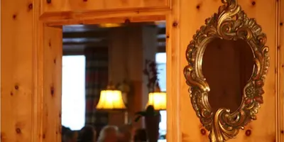 a mirror with a gold frame on a wooden wall at Hotel la Plaza in Corvara in Badia