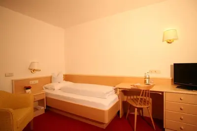 a bedroom with a bed and a desk with a television at Hotel la Plaza in Corvara in Badia