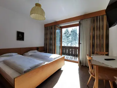 a bedroom with a bed and a desk and a window at Hotel la Plaza in Corvara in Badia