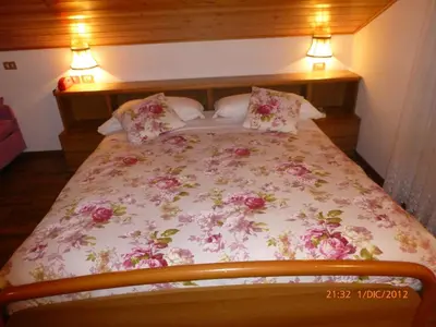 a bedroom with a bed with pink flowers on it at Hotel San Giovanni in Vigo di Fassa