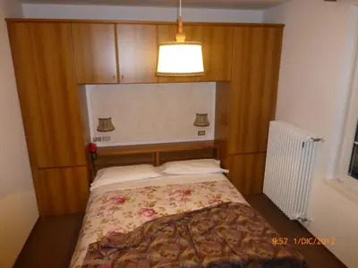 a bedroom with a bed with a wooden head board at Hotel San Giovanni in Vigo di Fassa