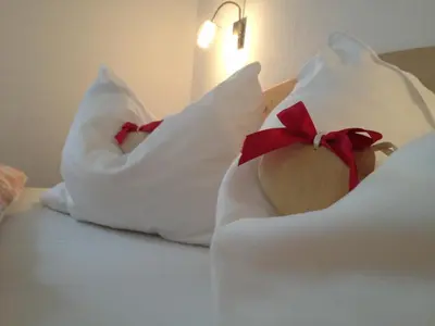 a bed with white pillows with red bows on it at Apartments Dolomie in Ortisei