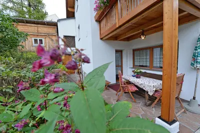 a patio with a table and chairs and flowers at Apartments Dolomie in Ortisei