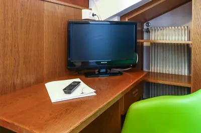 a desk with a television and a remote control on it at Guesthouse Pension Grafenstein in Merano