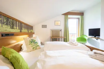 a hotel room with two beds and a television at Guesthouse Pension Grafenstein in Merano