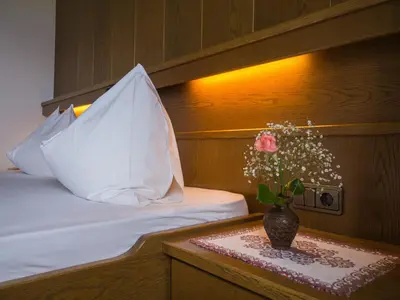 a bed with a vase with a flower on a table at Guesthouse Pension Grafenstein in Merano