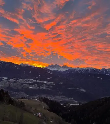 a sunset in the mountains with a red sky at Stocknerhof in Bressanone