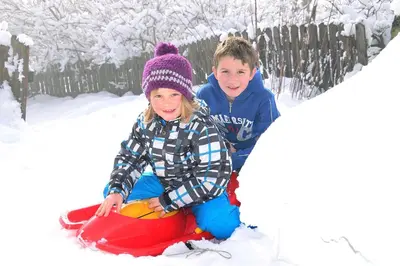 two children are playing in the snow on a sledge at Stocknerhof in Bressanone