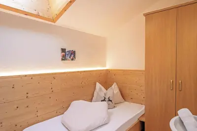 a small room with a bed and a cabinet at Residence Alpenrose in Bressanone