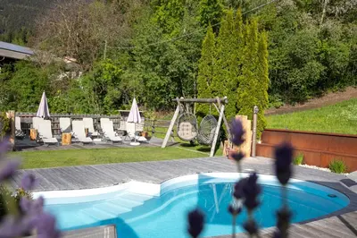 a swimming pool in a yard with chairs and a swing at Residence Alpenrose in Bressanone