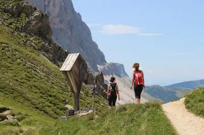 two people walking down a dirt road on a mountain at Residence Alpenrose in Bressanone