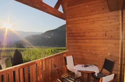 a patio with a table and chairs on a deck at Pröfinghof - Urlaub auf dem Biobauernhof in Parcines