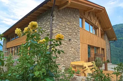 a stone house with yellow flowers in front of it at Pröfinghof - Urlaub auf dem Biobauernhof in Parcines