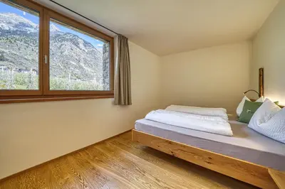 a bedroom with a bed and a large window at Pröfinghof - Urlaub auf dem Biobauernhof in Parcines