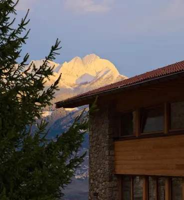 a snow covered mountain behind a building with a house at Pröfinghof - Urlaub auf dem Biobauernhof in Parcines