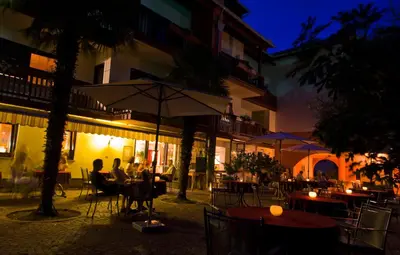 a group of people sitting at tables with an umbrella at Hotel Weingut Klosterhof in Caldaro