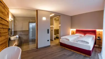 a bedroom with a large bed and a bathroom at Hotel Weingut Klosterhof in Caldaro