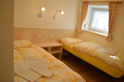 two beds in a small room with a window at Ciasa Andy in Badia