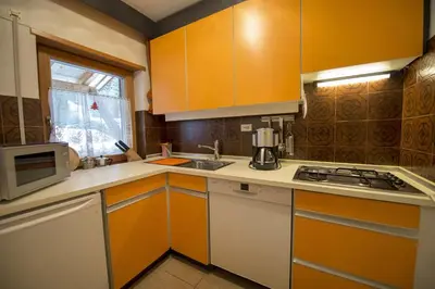 a kitchen with orange and white cabinets and a sink at Apartment Soval in Ortisei