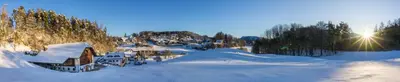 a snow covered village with the sun in the background at Appartments Neuhof in Collalbo