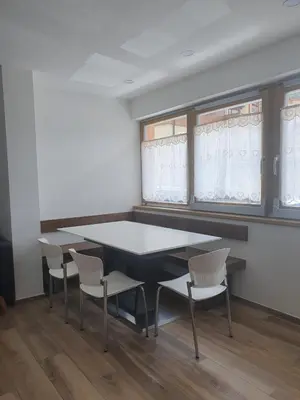 a table and chairs in a room with windows at Ciasa De Rosa in Pozza di Fassa