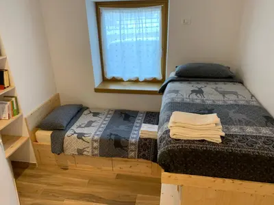 a bedroom with two beds and a window at Ciasa De Rosa in Pozza di Fassa
