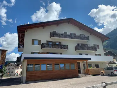 a large white building with wooden doors and balconies at Ciasa De Rosa in Pozza di Fassa