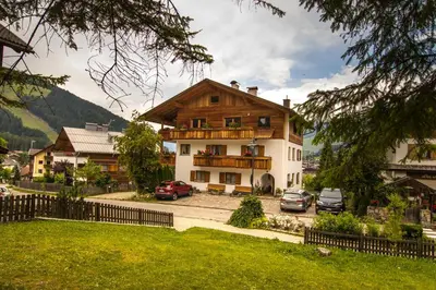 a house with cars parked in front of it at Ciasa Isidor in San Vigilio Di Marebbe