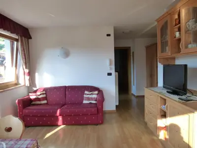 a living room with a red couch and a tv at Ciasa Isidor in San Vigilio Di Marebbe