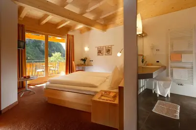 a hotel room with a bed and a balcony at Hotel Neuhausmühle in Vilpiano