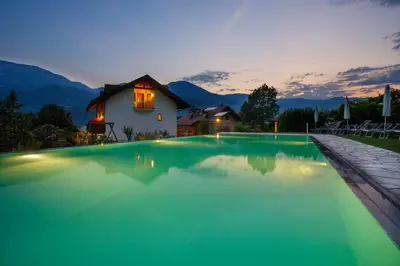 a swimming pool with a house in the background at Hotel Neuhausmühle in Vilpiano