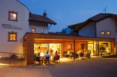 a group of people sitting at a table outside of a building at Hotel Neuhausmühle in Vilpiano