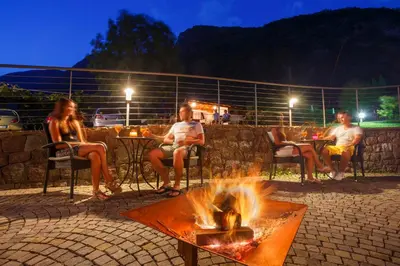 a group of people sitting around a fire pit at Hotel Neuhausmühle in Vilpiano