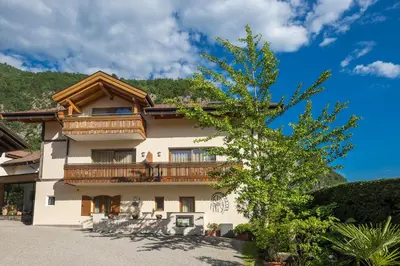 a large building with a balcony and a tree at Hotel Neuhausmühle in Vilpiano