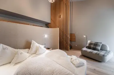 a bedroom with a large bed and a chair at Bad Ratzes in Siusi