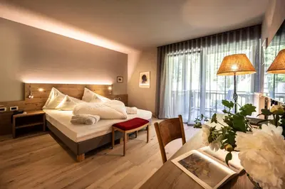 a hotel room with a bed and a desk and a room at Bad Ratzes in Siusi