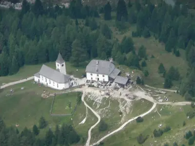 a large white house on a hill with a group of animals at Appartamenti Suttru in Badia