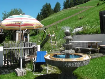 a fountain in a yard with an umbrella at Appartamenti Suttru in Badia