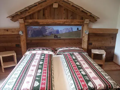 a bed in a room with a wooden wall at Aria D'Bosch in Badia