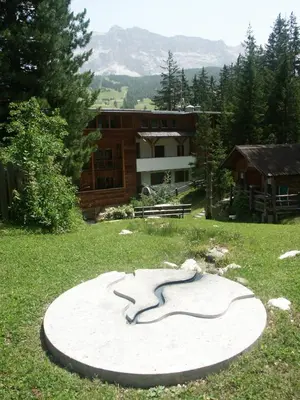a monument in the grass in front of a building at Aria D'Bosch in Badia
