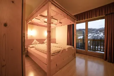 a bedroom with a canopy bed with a large window at Aria D'Bosch in Badia