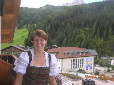 a woman standing on a balcony in front of a mountain at Garni Hotel Rezia in Selva di Val Gardena
